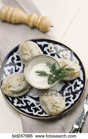 Stock Photograph - Dumplings and sauce on plate with fork and knife. Fotosearch