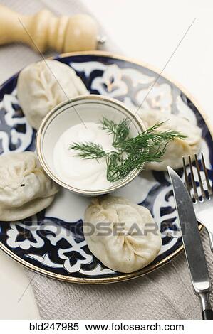 Stock Photography - Dumplings and sauce on plate with fork and knife. Fotosearch