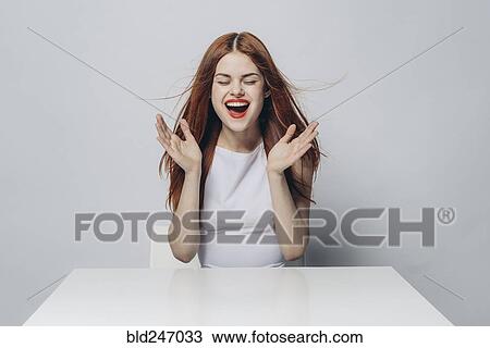 Excited Caucasian woman sitting at windy table View Large Photo Image Stock Image - Excited Caucasian woman sitting at windy table. Fotosearch