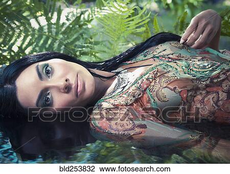 Stock Image - Exotic Hispanic woman laying in water. Fotosearch