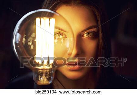 Face of Caucasian woman illuminated by energy efficient light bulb View Large Photo Image Picture - Face of Caucasian woman illuminated by energy efficient light bulb. Fotosearch