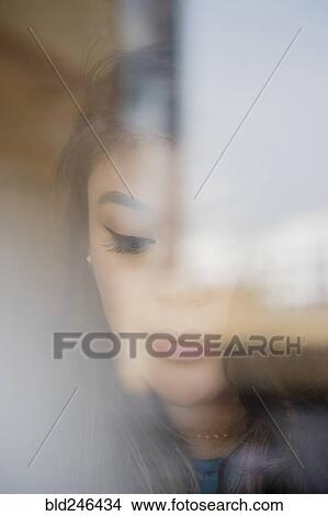 Picture - Face of pensive Mixed Race woman behind window. Fotosearch