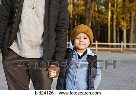 Father and son holding hands in park View Large Photo Image Stock Image - Father and son holding hands in park. Fotosearch