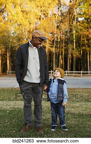 Stock Image - Father and son holding hands in park. Fotosearch