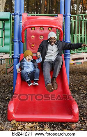 Father and son on playground slide in park View Large Photo Image Stock Image - Father and son on playground slide in park. Fotosearch