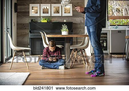 Father and son texting on cell phones View Large Photo Image Stock Image - Father and son texting on cell phones. Fotosearch
