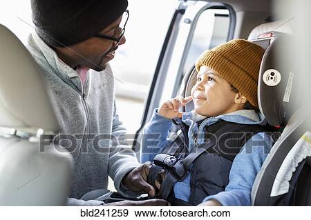 Father buckling son in car seat View Large Photo Image Stock Photo - Father buckling son in car seat. Fotosearch