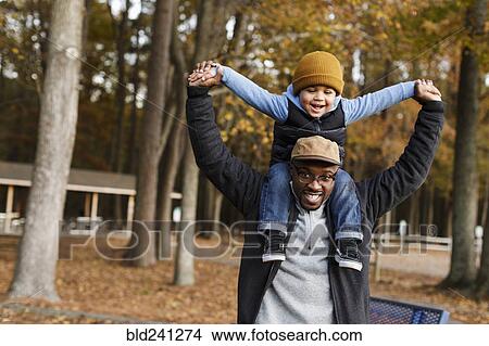 Father carrying son on shoulders in park View Large Photo Image Picture - Father carrying son on shoulders in park. Fotosearch