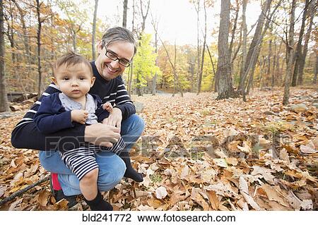 Stock Image - Father holding baby son outdoors in autumn. Fotosearch