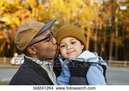 Father kissing son on cheek in park View Large Photo Image Picture - Father kissing son on cheek in park. Fotosearch
