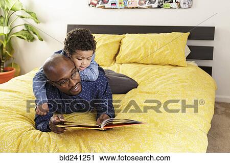 Father reading book to son on bed View Large Photo Image Stock Image - Father reading book to son on bed. Fotosearch