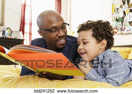 Father reading book to son on bed View Large Photo Image Stock Image - Father reading book to son on bed. Fotosearch