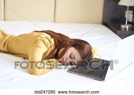 Fatigued Caucasian woman sleeping on bed near laptop View Large Photo Image Stock Photography - Fatigued Caucasian woman sleeping on bed near laptop. Fotosearch