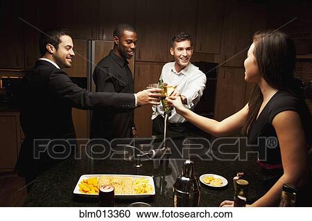 Stock Image - Friends drinking in kitchen at party. Fotosearch