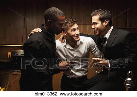 Stock Image - Friends drinking in kitchen at party. Fotosearch