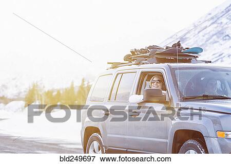 Stock Photo - Friends driving in car with snowboards in winter. Fotosearch