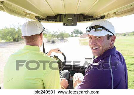 Stock Image - Friends driving on golf course. Fotosearch