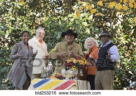Stock Photograph - Friends enjoying wine and cocktails outdoors. Fotosearch