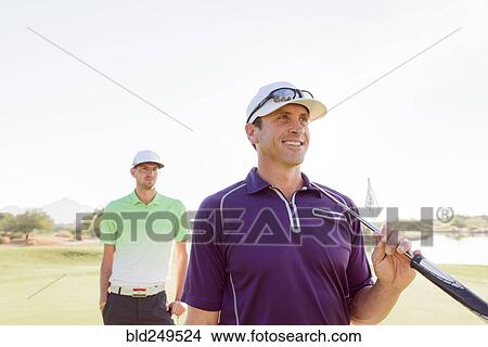 Friends holding golf clubs on golf course View Large Photo Image Picture - Friends holding golf clubs on golf course. Fotosearch