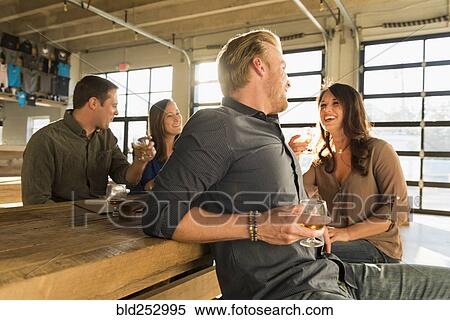Stock Photography - Friends laughing in brew pub. Fotosearch