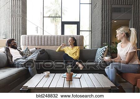 Stock Image - Friends laughing in lounge. Fotosearch