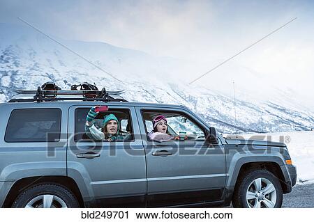 Stock Image - Friends photographing from car in winter. Fotosearch