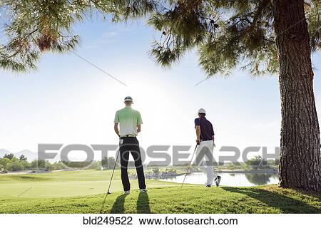 Stock Image - Friends standing on golf course. Fotosearch