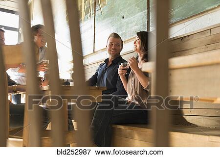 Friends talking in brew pub behind chair View Large Photo Image Stock Photo - Friends talking in brew pub behind chair. Fotosearch