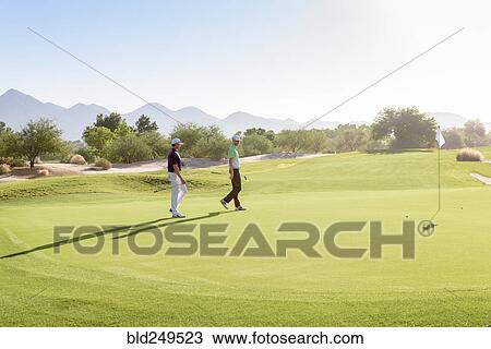 Friends walking on golf course View Large Photo Image Stock Image - Friends walking on golf course. Fotosearch