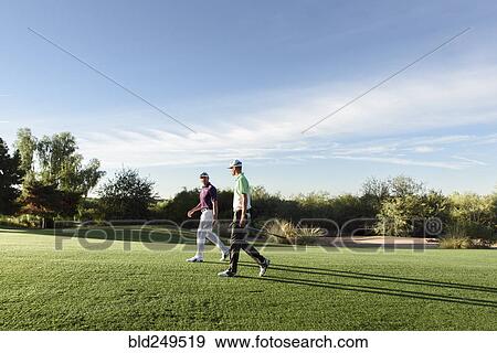 Stock Photo - Friends walking on golf course. Fotosearch