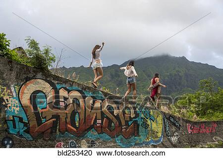 Stock Image - Friends walking on graffiti wall near mountain. Fotosearch