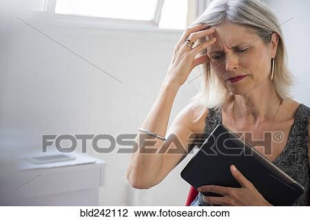 Frustrated Caucasian woman holding digital tablet suffering headache View Large Photo Image Stock Image - Frustrated Caucasian woman holding digital tablet suffering headache. Fotosearch