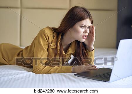Frustrated Caucasian woman laying on bed using laptop View Large Photo Image Stock Image - Frustrated Caucasian woman laying on bed using laptop. Fotosearch