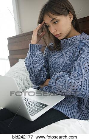 Frustrated Mixed Race woman using laptop in bed View Large Photo Image Stock Photo - Frustrated Mixed Race woman using laptop in bed. Fotosearch