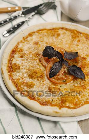 Stock Photo - Garnish and tomatoes on pizza. Fotosearch