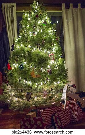 Stock Image - Gifts under illuminated Christmas tree. Fotosearch