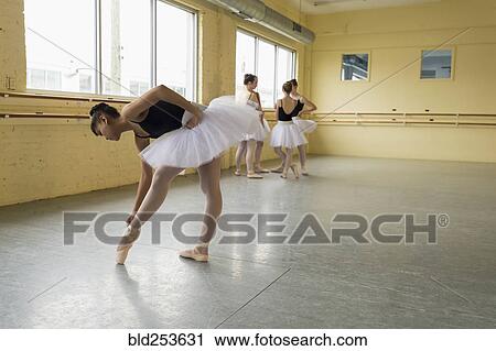 Stock Image - Girl checking shoe in ballet studio. Fotosearch