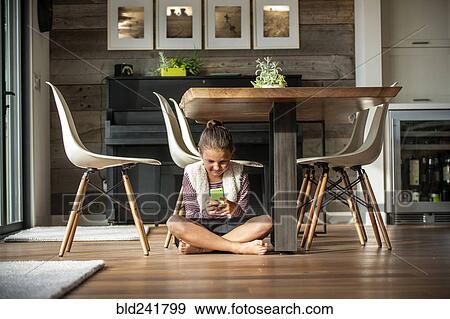 Stock Photo - Girl sitting on floor texting on cell phone. Fotosearch