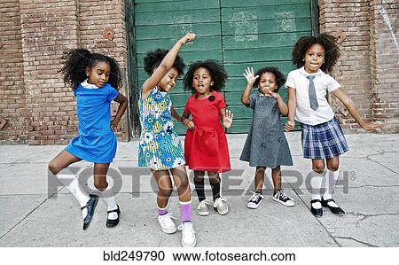 Stock Image - Girls dancing on city sidewalk. Fotosearch