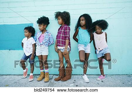 Picture - Girls leaning in blue wall. Fotosearch