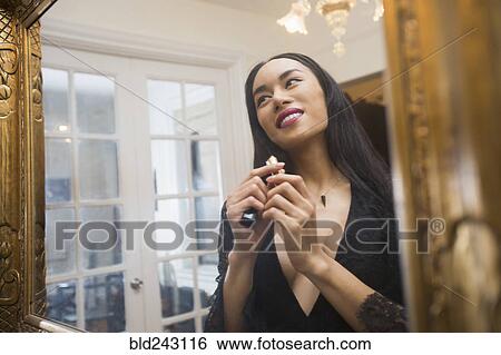 Glamorous transgender Thai woman applying lipstick in mirror View Large Photo Image Stock Photograph - Glamorous transgender Thai woman applying lipstick in mirror. Fotosearch