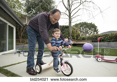 Grandfather pushing grandson on tricycle View Large Photo Image Stock Image - Grandfather pushing grandson on tricycle. Fotosearch
