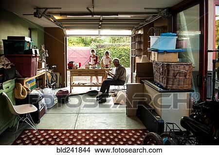 Picture - Grandfather watching granddaughters building birdhouse in garage. Fotosearch