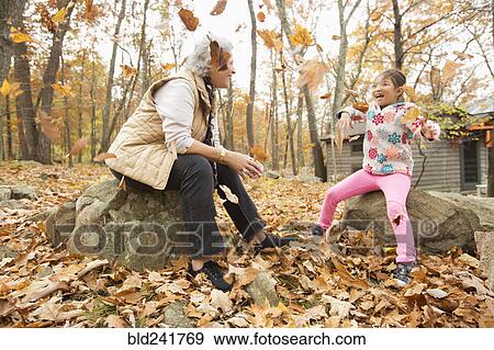 Stock Photo - Grandmother and granddaughter playing with autumn leaves. Fotosearch