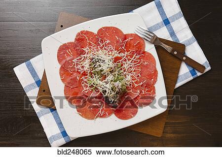 Stock Photography - Grated cheese on plate of sliced meat. Fotosearch
