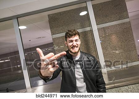 Stock Image - Grinning Caucasian man making obscene gesture with finger. Fotosearch