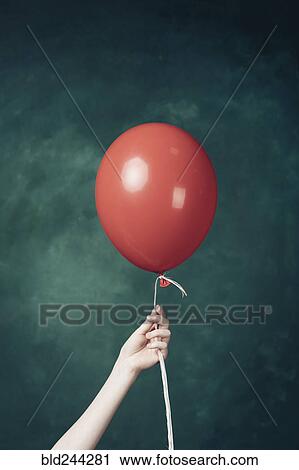 Stock Image - Hand holding red balloon. Fotosearch