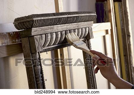 Picture - Hand of Caucasian man using paintbrush on picture frame. Fotosearch