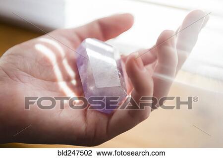 Stock Image - Hand of Caucasian woman holding crystal. Fotosearch