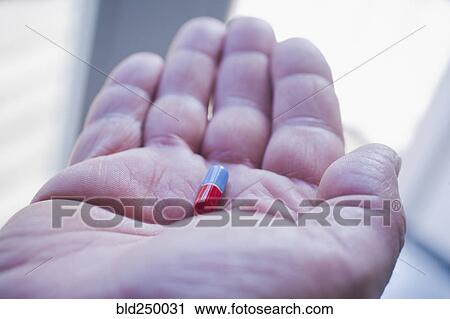 Stock Image - Hand of Hispanic man holding pill. Fotosearch